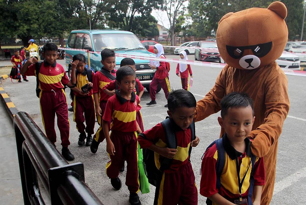 Murid-murid mesra disambut maskot Teddy Bear ketika hadir pada hari pertama sesi persekolahan 2023/2024 di Sekolah Kebangsaan Tasik Damai hari ini.