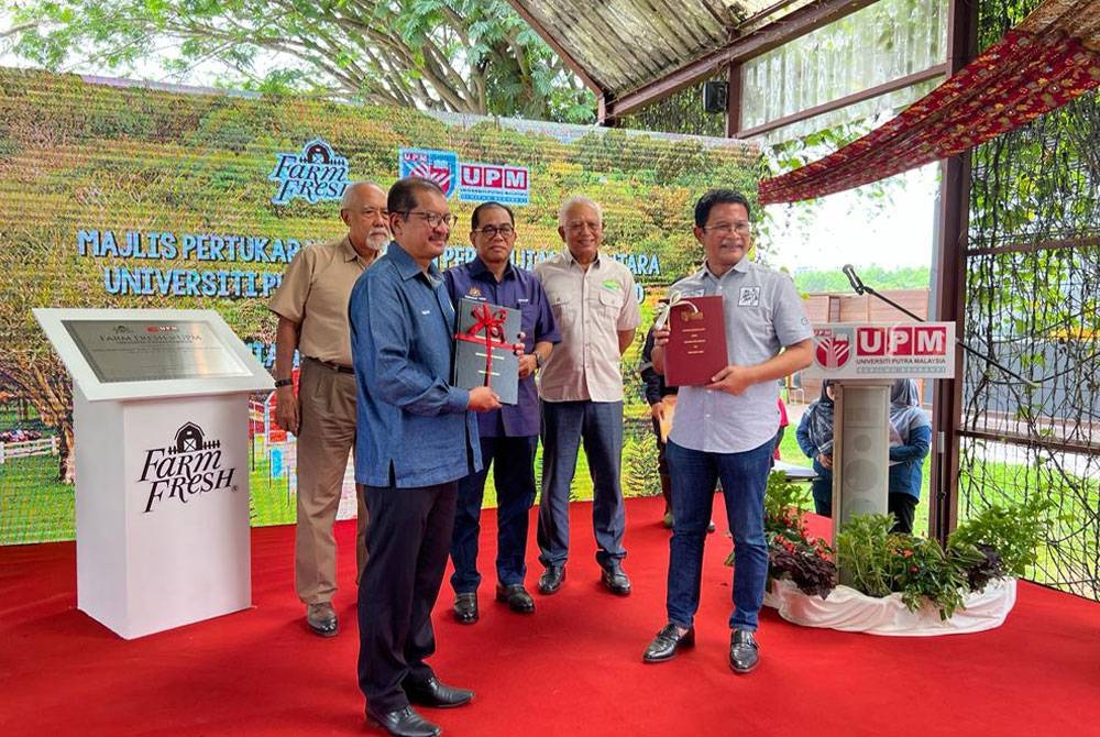 Azmi (kanan) dan Mohd Roslan (kiri) ketika sesi pertukaran MoA bagi pembangunan ICOE Tenusu di Ladang 16 UPM pada Isnin.