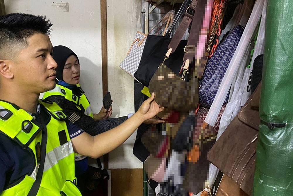 Anggota KPDN memeriksa barang dalam serbuan di tujuh stor di Jalan Petaling, Kuala Lumpur pada Isnin.