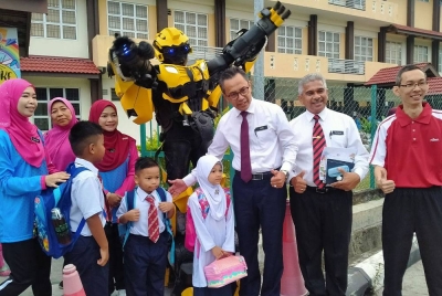 Mohamad Fauzi (tiga dari kanan) bersama 'Bumblebee' yang menyambut kehadiran murid pada hari pertama sesi persekolahan di SK Meru Raya di sini pada Isnin.