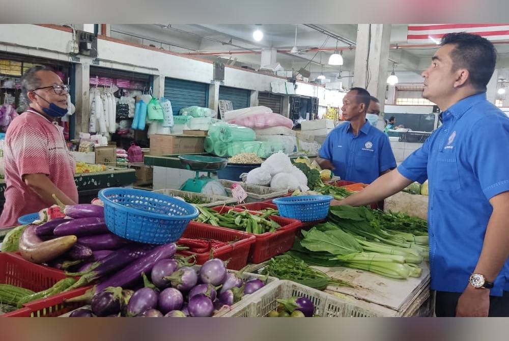 Mohamad Yusrizal (kanan) bertanyakan harga sayuran yang dijual di Pasar Besar Alor Setar pada Rabu.