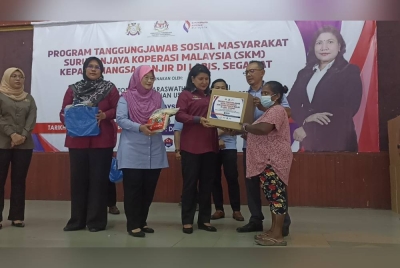 K. Saraswathy ( tiga dari kanan) menyerahkan bakul makanan kepada mangsa banjir di Dewan Serbaguna Majlis Daerah Labis pada Khamis.