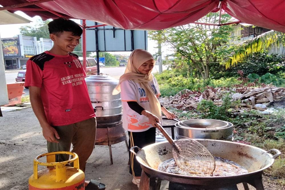 Meersyam (kiri) menggoreng ayam di gerainya di Wakaf Che Yeh.
