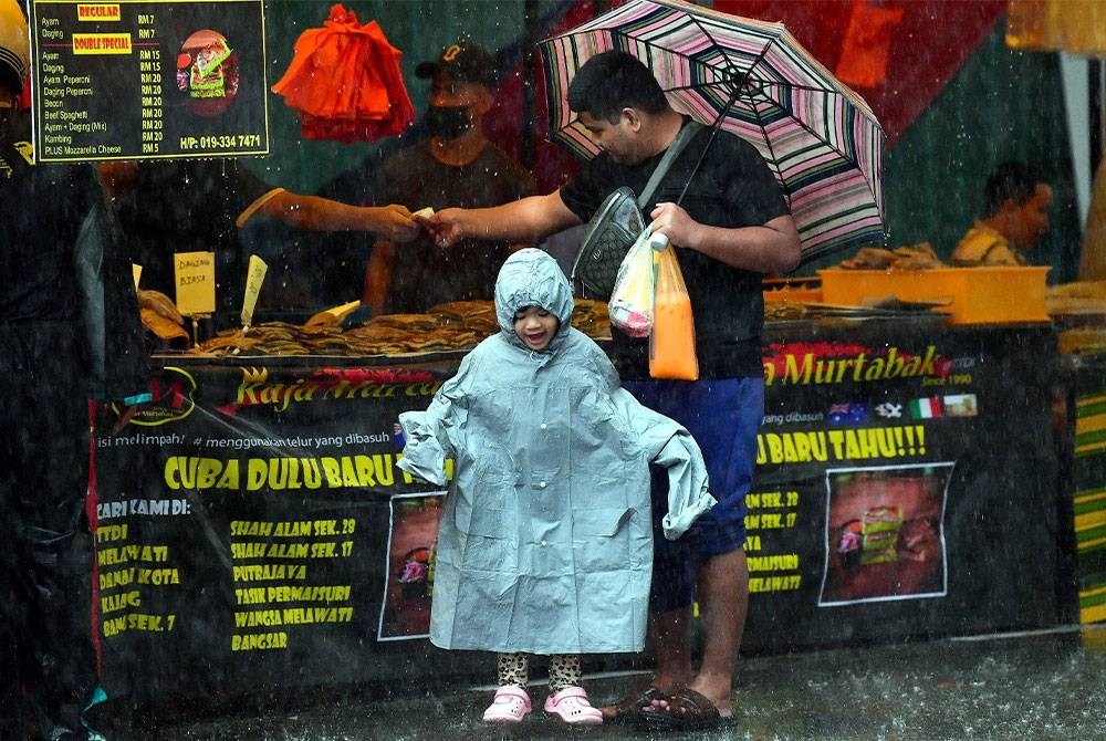 Reaksi seorang kanak-kanak
yang bermain hujan ketika tinjauan orang ramai keluar membeli juadah berbuka puasa pada hari pertama Ramadan di bazar Ramadan TTDI, pada Khamis. - Foto Bernama
