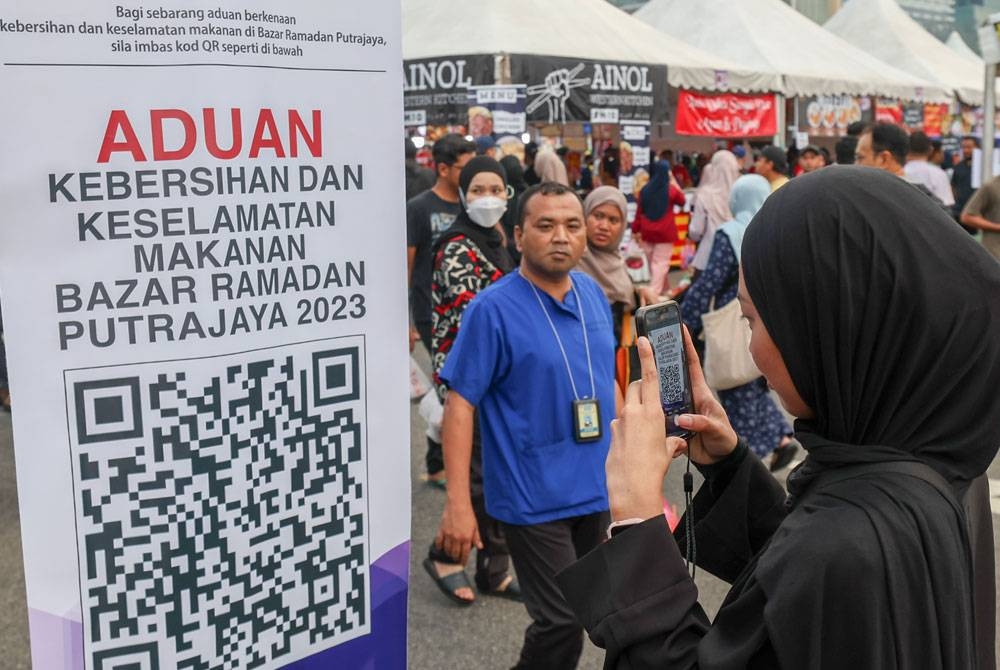 Seorang pengunjung mengimbas kod QR Aduan Kebersihan dan Keselamatan Makanan di Bazar Ramadan Putrajaya 2023 di Presint 3 hari ini. - Foto Bernama