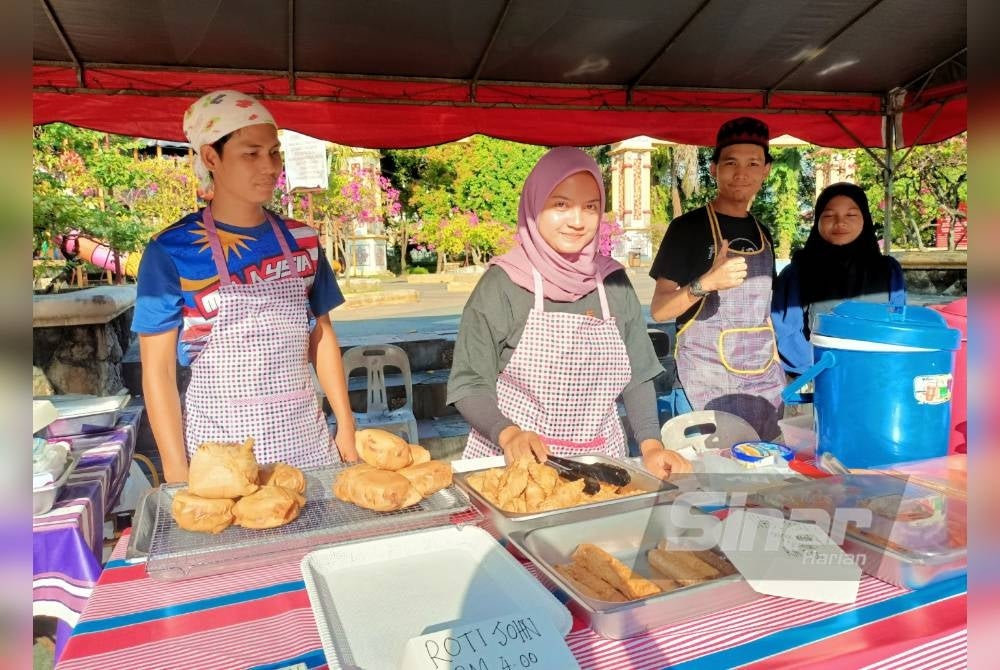 Izzati (dua dari kiri) menunjukkan jualan roti khurasan dan roti john di bazar Ramadan Rahmah di People's Park ketika tinjauan pada Jumaat.