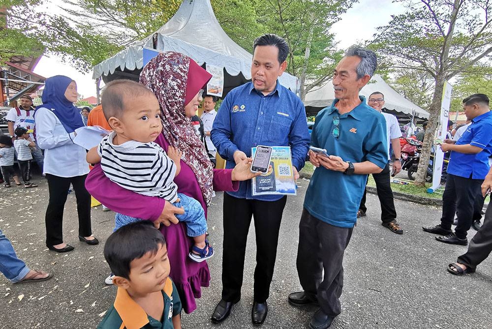 Shaharuddin (dua dari kanan) melihat salah seorang pelanggan yang telah siap mendaftar dan menerima sumbangan tunai RM20 yang dimasukkan ke e-wallet di Bazar Ramadan Rahmah Binjai Rendah di Marang, Terengganu.