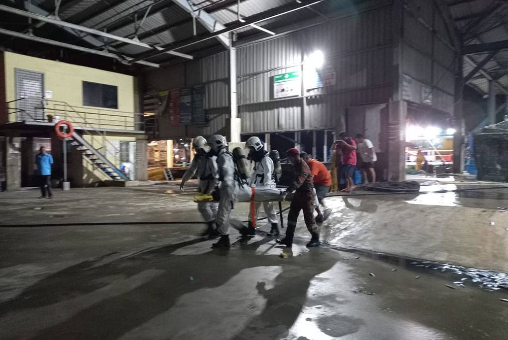 Pasukan bomba membantu mangsa yang terhidu gas beracun di sebuah jeti di Sepanggar, Kota Kinabalu untuk dihantar ke hospital.