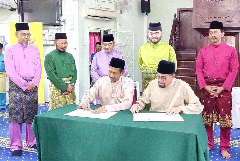 Pengurus Besar YIDE, Nur Mohd Razali Abdullah (duduk kiri) dan Ustaz Don (duduk kanan) menandatangani Memorandum Persefahaman (MoU) sambil disaksikan Tengku Amir Shah (belakang dua dari kanan) dan Mazlan (belakang tiga dari kiri) pada Majlis Penyampaian Sumbangan YIDE kepada anak yatim di Masjid Kampung Sungai Terap di sini pada Ahad.