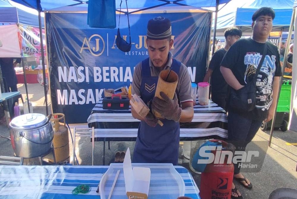 Mohd Afif mengetuk nasi beriani keluar dari buluh. Ketukan pada buluh berjaya menarik pengunjung bazar Ramadan untuk merasai keenakan nasi beriani tersebut.