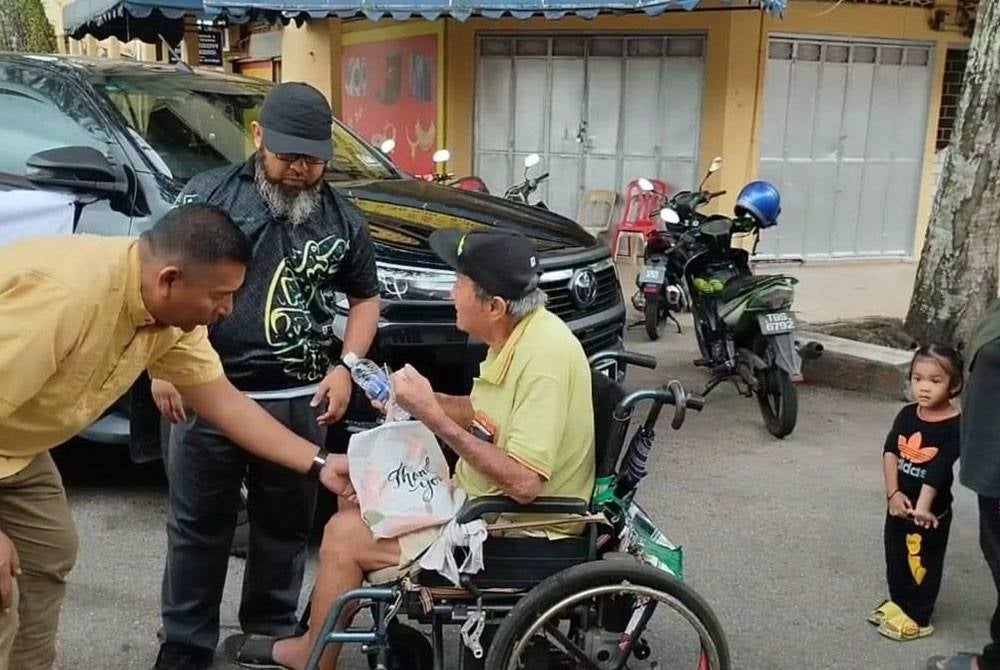 Badrul Jamili (kiri) dan Asmadi (dua dari kiri) menyerahkan juadah iftar kepada golongan OKU.