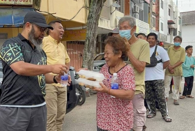 Asmadi (kiri) bersama Badrul Jamili (dua dari kiri) menyerah juadah kepada komuniti rentan di Jalan Wong Ah Jang.