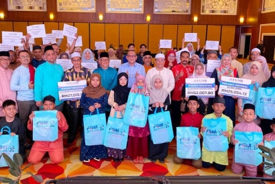 Wan Munadi (tujuh dari kanan) bersama penerima dan warga pendidik di Kelantan semasa Majlis Iftar Ramadan YGMB pada Ahad.
