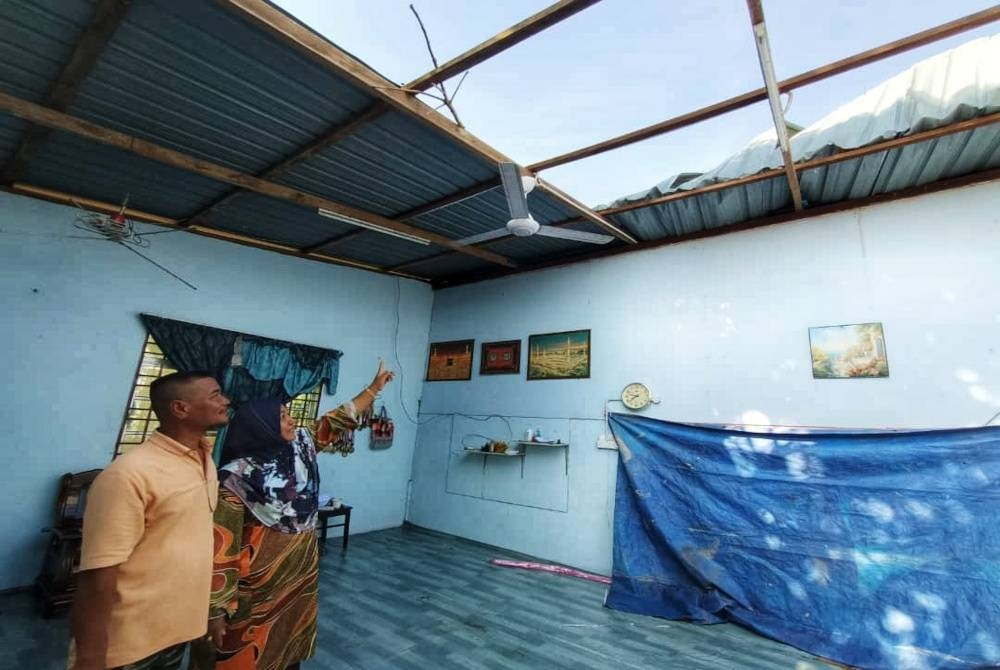 Pairus bersama suaminya, Abdul Latif Abdullah, 51 menunjukkan bahagian ruang tamu rumah mereka yang terjejas.