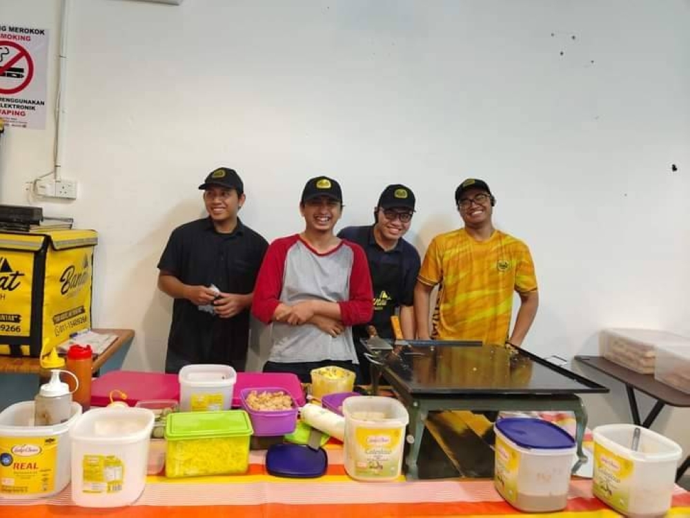 Kakitangan Banat Sandwich yang kuyup ketika mengalihkan khemah yang terbang. (Foto: Banat Sandwich)