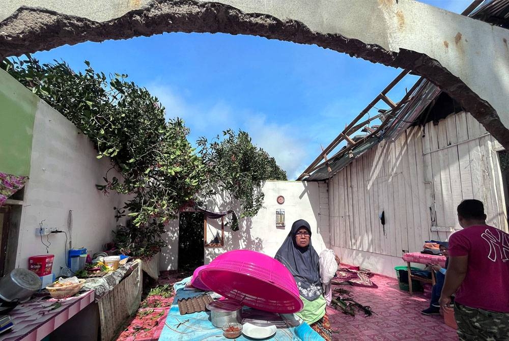 Hasmah mengemas barangan di bahagian ruang dapur rumahnya yang mengalami kerosakan selepas dibadai ribut petang semalam. - Foto Bernama