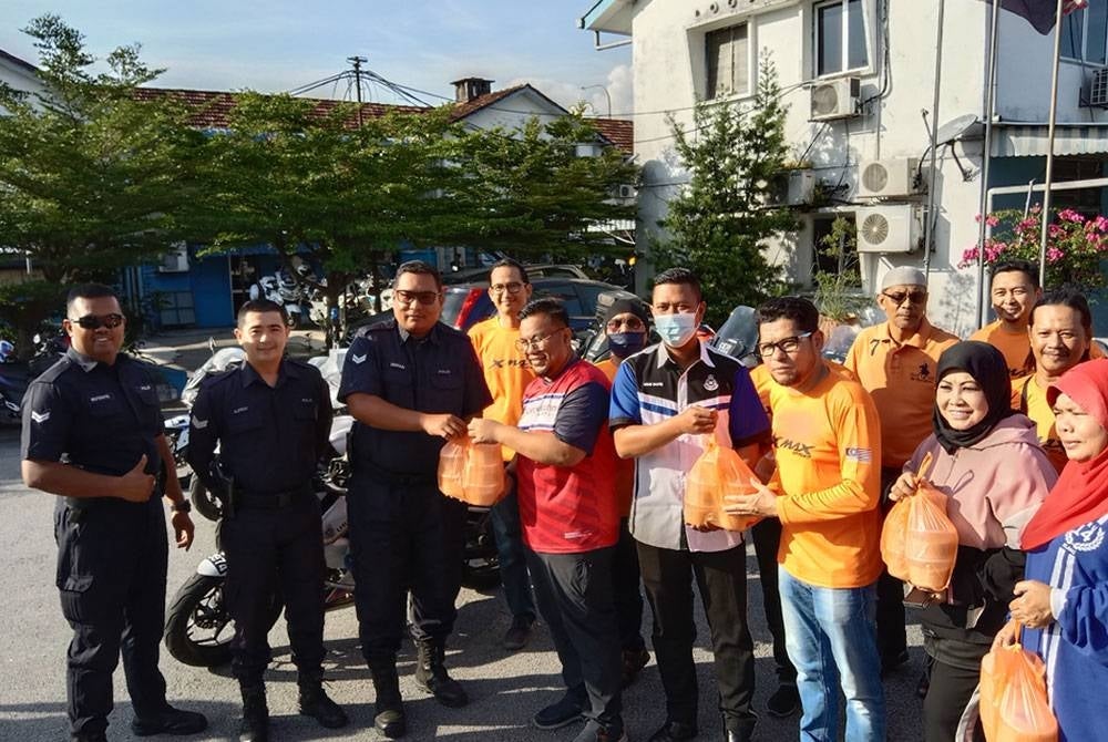 Anggota polis menerima bubur lambuk dalam program Ziarah Kasih Ramadan yang dianjurkan Kelab Xmax Selkang di sini pada Isnin.