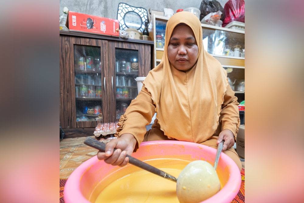 Noriah mengacau adunan untuk membuat kuih kapit iaitu gula, tepung gandum dan telur. - Foto Bernama