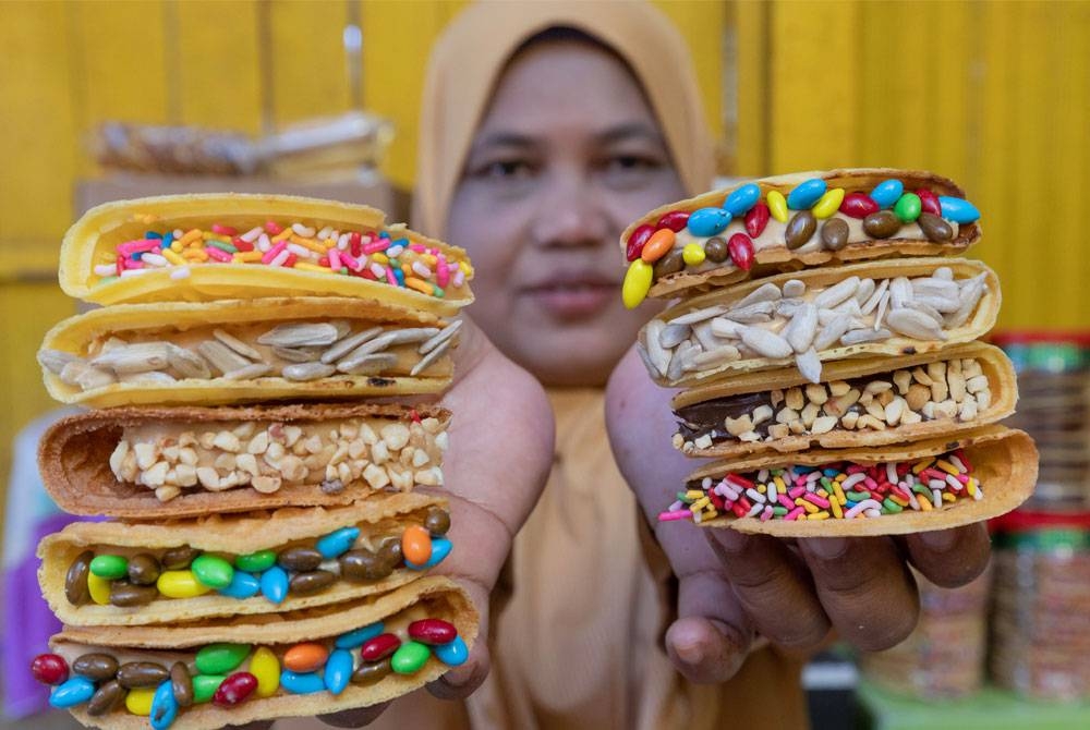 Noriah menunjukkan empat perasa sebagai inti tambahan pada kuih kapit seperti salutan kuaci coklat, kuaci biasa, coklat keju dan kacang. - Foto Bernama