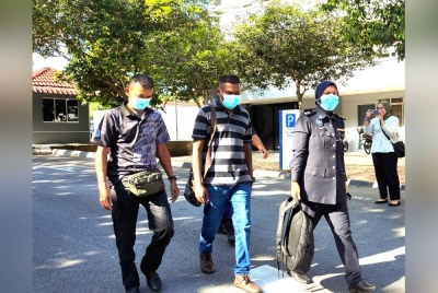 Muhammad Soleh (tengah) diiringi polis di mahkamah.