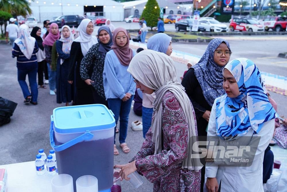 Pengunjung yang hadir beratur mengambil air minuman yang disediakan.