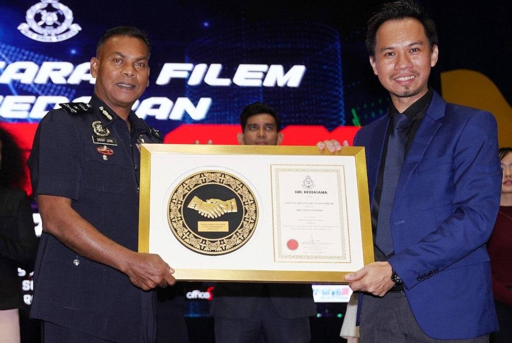 Mohamed Usuf (kiri) menyampaikan sijil kerjasama PDRM dan Dream Film kepada Lin Loong sempena majlis pelancaran filem Oppa di Maktab PDRM pada Rabu.