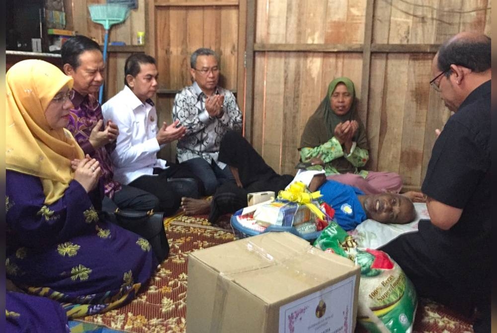 Nazran (dua dari kiri) dan Dr Wan Nazariah (kiri) turut mendoakan kesihatan Che Aznan.