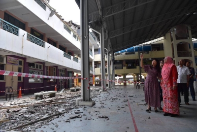 Hui Ying (kiri) melihat keadaan bumbung runtuh di SMK Cheras Jaya pada Khamis.