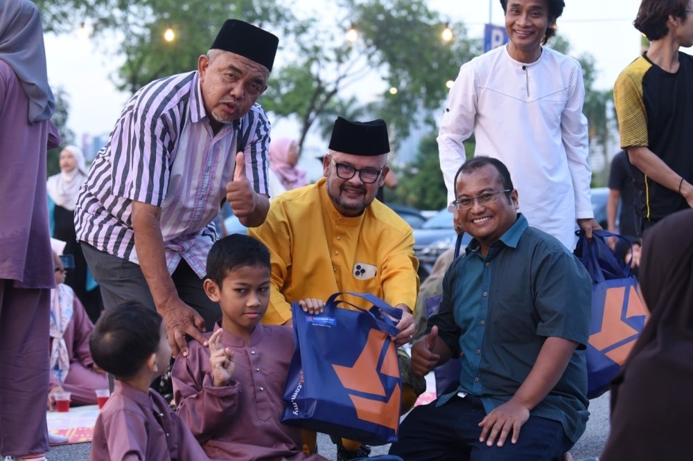 
Harith (tengah) memberi sumbangan makanan daripada Bank Rakyat.