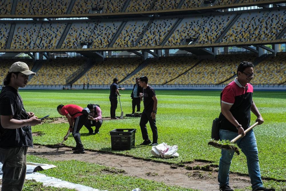 Orang ramai mengambil rumput padang Stadium Nasional Bukit Jalil yang dibuka kepada pengunjung sehingga petang Jumaat sebelum kerja-kerja memasang rumput baharu jenis Zeon Zoysia bagi menggantikan rumput Cow Grass di padang tersebut. - Foto: Bernama