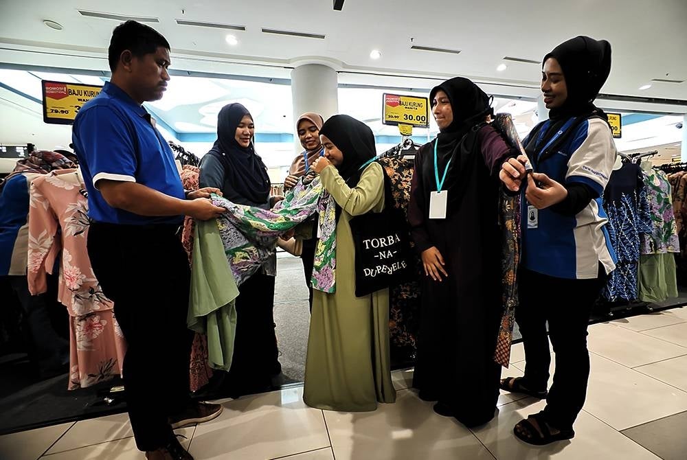 Mohd Norlisam (kiri) dan Siti Yusnita (dua dsri kiri) membantu anak yatim memilih baju raya.