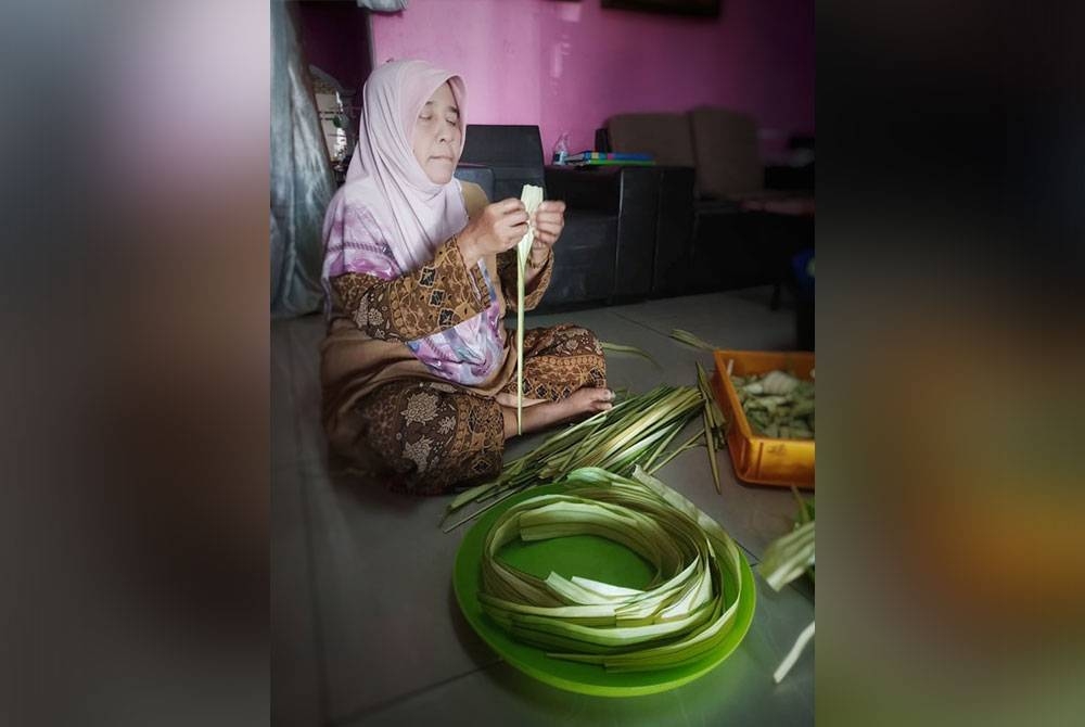 Ibunya, Siti Mariam Mustaffa, 65, turut membantu membuka daun palas untuk menyiapkan tempahan ketupat.