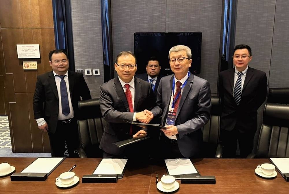 Hock San (dua dari kanan) dan Xiu Guo menyerahkan dokumen perjanjian masing-masing yang diadakan di China World Hotel Beijing, China.