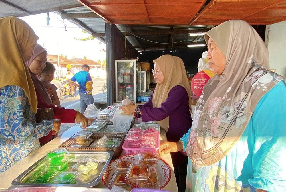 Siti Maimunah (kanan) dan anak-anak tidak menang tangan melayan pelanggan di kedai mereka di Kampung Tanjong Baru, Taman Buaya, Kota Bharu.