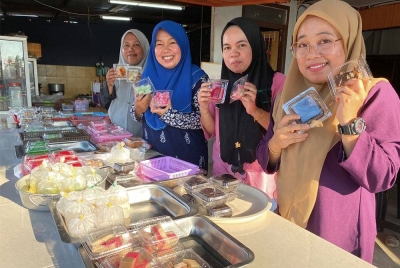 Empat anak perempuan Siti Maimunah menunjukkan sebahagian daripada 1,000 peket kuih-muih yang dijual dengan harga RM1.