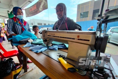 Roswati (kanan) melayan pelanggan yang mendapatkan khidmatnya di Taman Sri Muda.