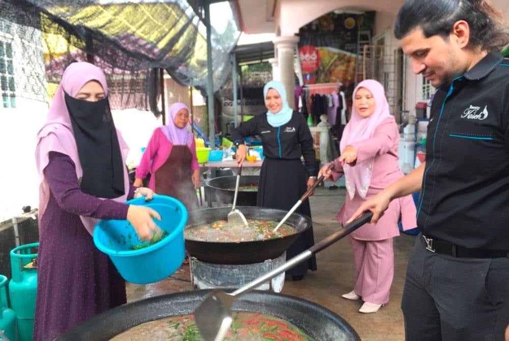 Zurawati (kiri) menyediakan lauk untuk diagihkan kepada asnaf-asnaf. 