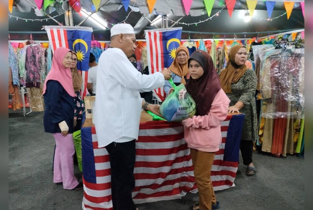 Mohd Yusoff memberikan pakaian percuma kepada seorang kanak-kanak yang datang ke Butik Rahmah di RUTC Klebang Besar di sini, pada malam Isnin.