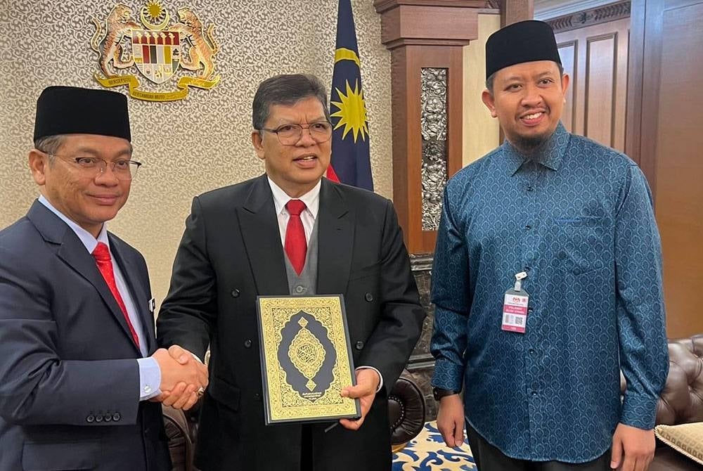 Mohd. Na’im (kiri) menyerahkan sumbangan al-Quran kepada Johari.