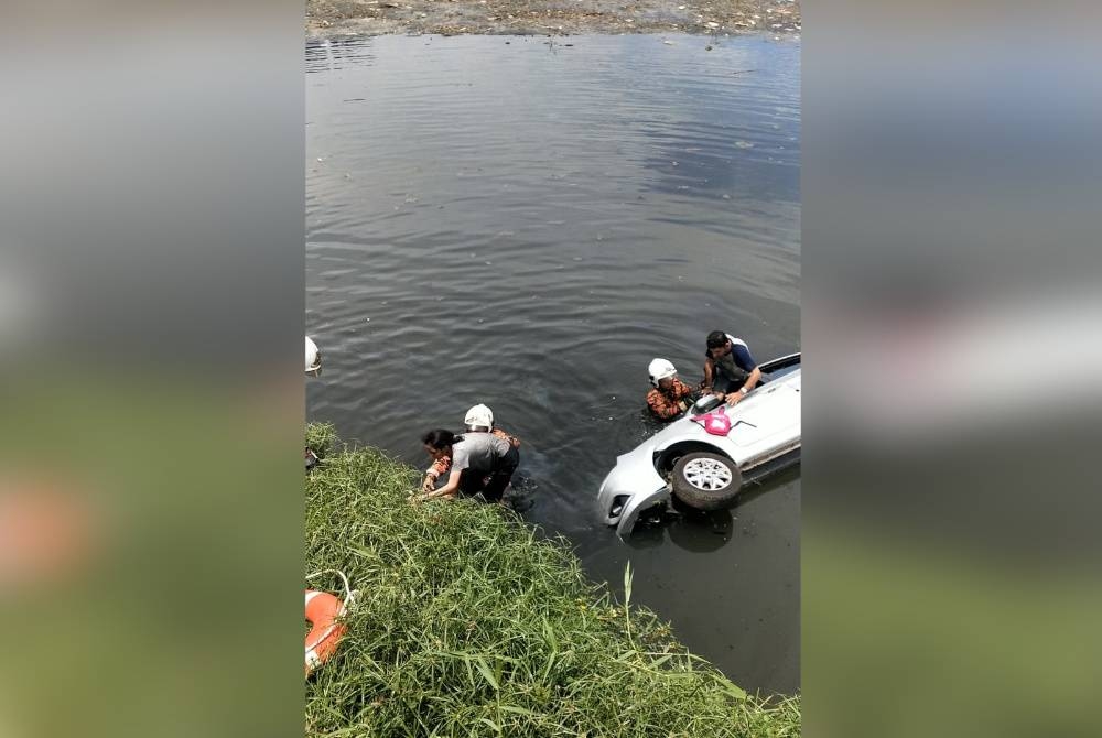 Anggota Bomba menyelamatkan tiga beranak selepas kenderaan yang dinaiki mereka terbabas lalu terjunam ke dalam kolam takungan banjir berhampiran bulatan Mergastua, Jalan 3/40 Taman Pusat Kepong pada Selasa.