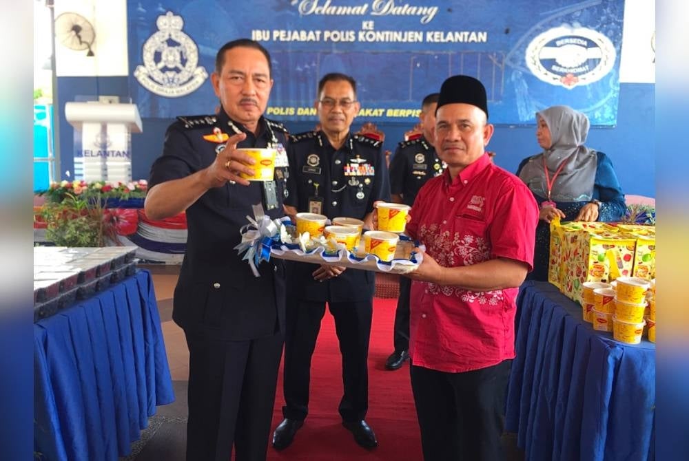 Awang (kanan) menyerahkan bubur lambuk kepada Muhamad Zaki (kiri) untuk agihan kepada kakitangannya.