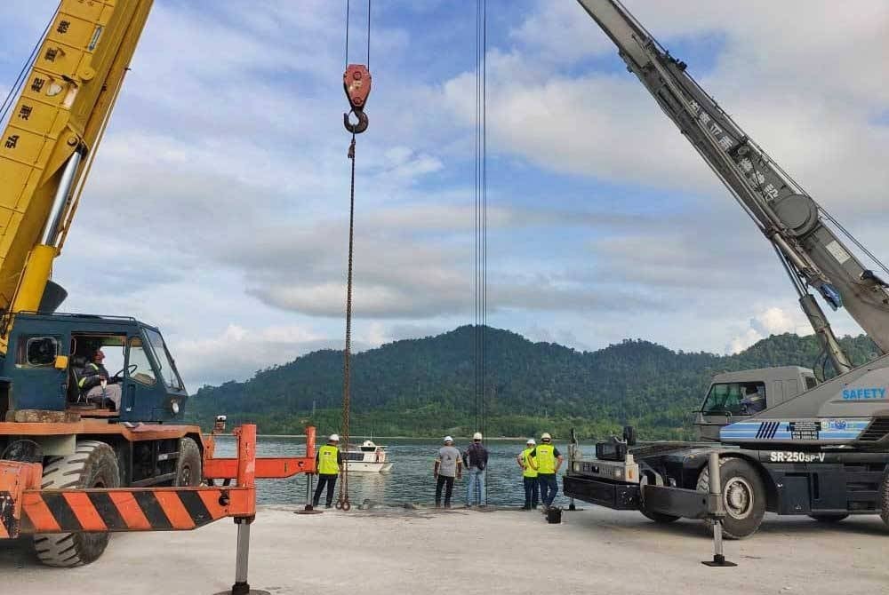 Dua unit kren dari pelabuhan dalam tindakan untuk membawa naik lori ke tebing.- Foto Bomba Perak