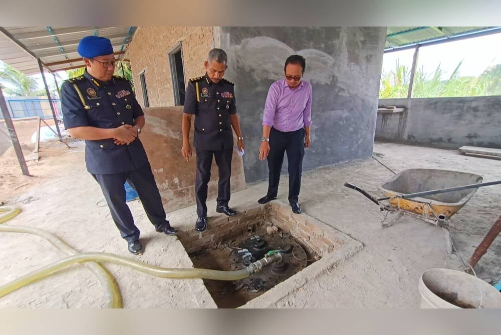 Kamalludin (kanan) menunjukkan satu daripada dua tangki buatan bawah tanah yang ditemui ketika serbuan sebuah premis di Kampung Kepayang, Simpang Pulai pada Selasa.