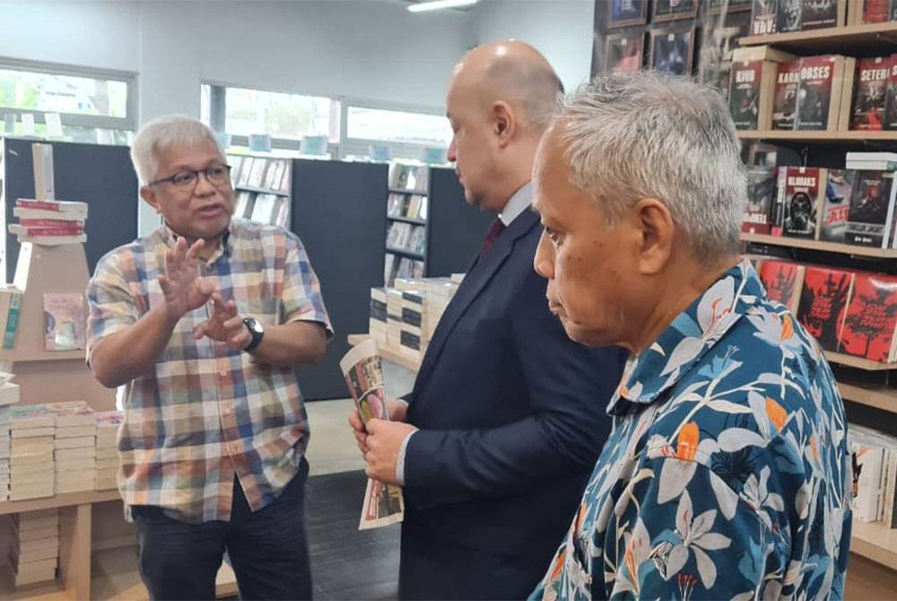Ravshan (tengah) diberikan penerangan berkaitan jualan buku Karangkraf.