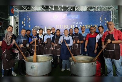 Mohammad Hanis (lima dari kanan) bergambar bersama Ahli Lembaga Pengarah bersama-sama Jawatankuasa Pengurusan Bank Rakyat menyediakan bubur lambuk.