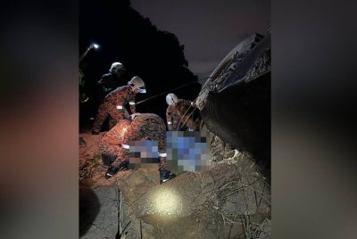 Anggota bomba menjalankan operasi mengeluarkan mayat kedua-dua mangsa yang terperangkap dalam jengkaut terbalik di Simpang Pulai. - Foto Ihsan JBPM Perak