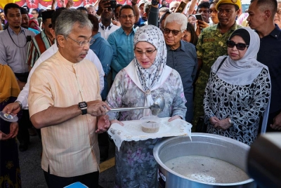 Al-Sultan Abdullah dan Tunku Azizah berkenan mengisi bubur lambuk ke dalam bekas ketika melawat Bazar Ramadan Tanjong Tokong pada Khamis. - Foto Bernama