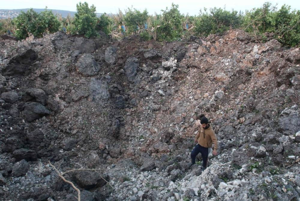 Seorang lelaki berjalan di atas kawah yang terbentuk akibat serangan udara Israel di Al Qulaylah, di pinggir bandar Tyre, selatan ibu negara Lubnan pada Jumaat. - Foto AFP