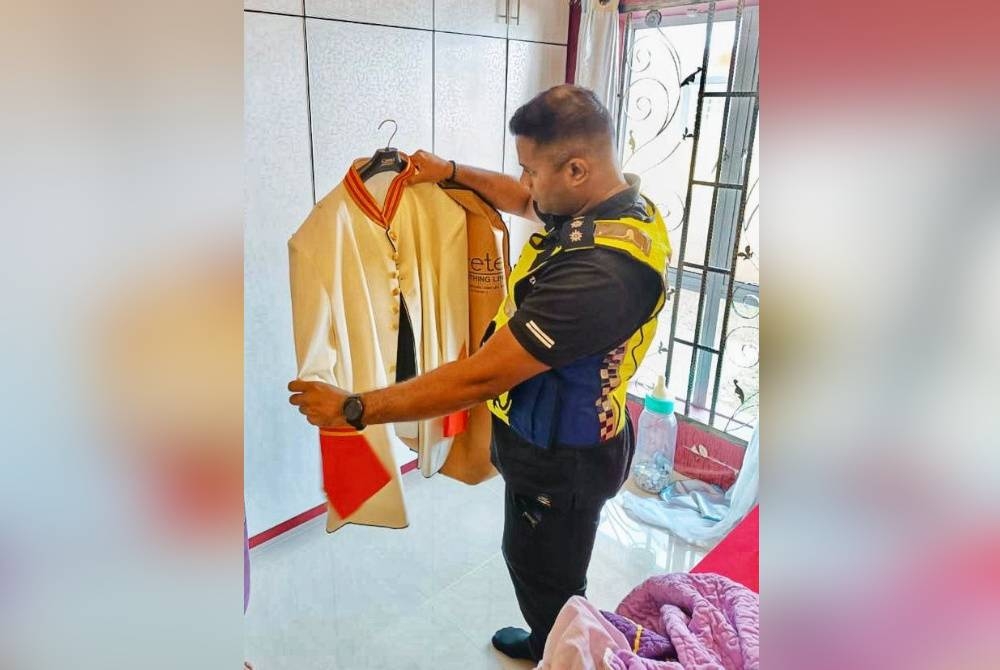 Anggota polis merampas pakaian istiadat yang ditemui dalam serbuan tersebut. - Foto PDRM