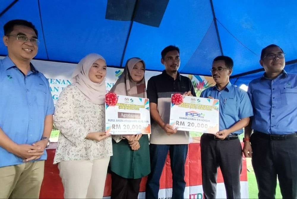 Abdul Rashid (dua kanan) ketika menyampaikan replika cek kepada peserta ladang kontrak.